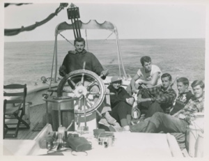 Image of Group on quarter deck; Stan at wheel, Miriam MacMillan, Andy, Dave, Horace, and Ed